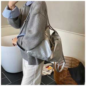 Detail of silver metallic tote bag with texture and golden buckle on shoulder strap