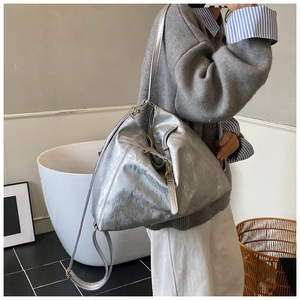 Detail of silver metallic textured tote bag featuring modern triangular pleats and gold buckle