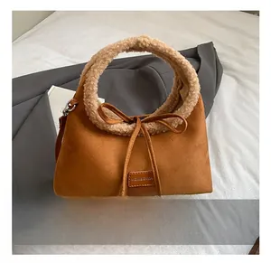 Close-up of brown suede tote bag with faux fur handles and decorative bow knot detail