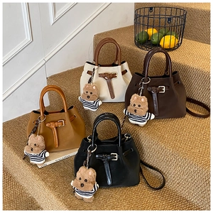 Détails de sacs seaux en daim en quatre couleurs avec breloques d'ours sur l'escalier