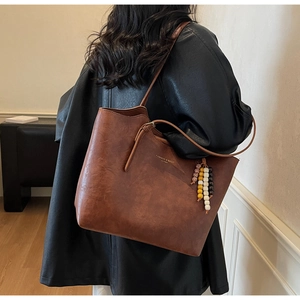 Dettaglio della borsa tote vintage in pelle marrone con perline etniche e logo moda