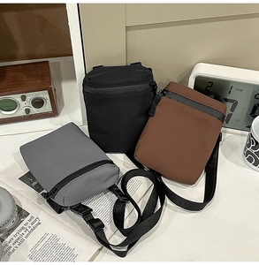 Close-up of three nylon crossbody bags in grey, black and brown with adjustable straps