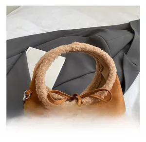 Detail showing plush faux shearling trim and bow tie on caramel suede handbag