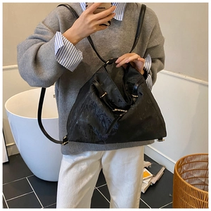 Close-up of black textured convertible tote bag with gold hardware on a lifestyle model