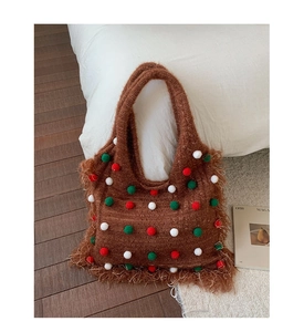 Close-up of brown knit tote bag with colorful pom-poms and fine fringe details