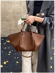 Detail of vintage brown wing-shaped leather tote bag with metal rivet accents