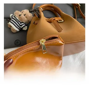 Gros plan du sac fourre-tout en daim marron avec ferrures dorées et pochette zippée assortie