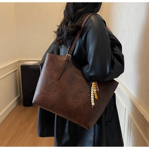 Dettaglio della borsa tote in pelle marrone scuro con ciondolo di perline colorate