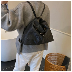 Detail of a black triangular backpack with glossy texture and adjustable metal buckles