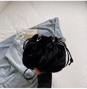 Vue de dessus d'un sac seau en fausse fourrure noire sur denim avec fine bandoulière