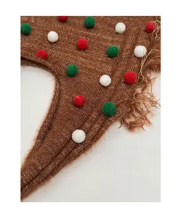 Detail of a brown knit tote bag with colorful plush balls and long tassel fringe