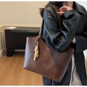 Dettaglio della texture della borsa tote marrone vintage con logo e ciondolo di perline