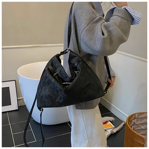 Detailed view of large black tote bag with textured surface and gold metal buckle accents