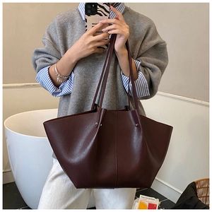 Detail of dark reddish-brown leather tote bag with wing silhouette and large capacity