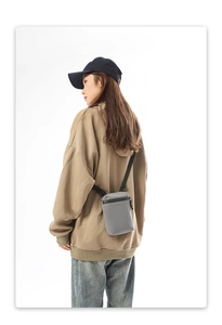 Gray compact crossbody bag with waterproof zipper shown on model for daily lifestyle