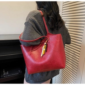Dettaglio della borsa tote in pelle rossa martellata con nappa di perline di legno colorate