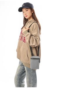 Gray compact crossbody phone bag with adjustable wide strap shown on a model