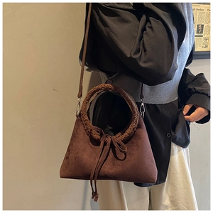 Detail of brown suede crossbody bag featuring soft plush faux shearling round handles