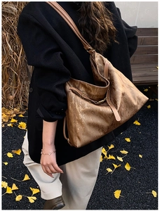 Detail of vintage brown metallic tote bag with wrinkled texture and leather strap in autumn setting
