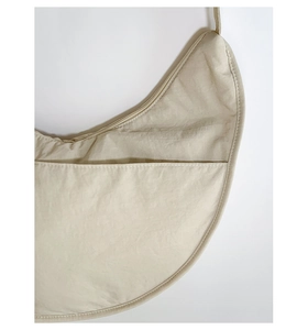 Detail of beige nylon dumpling bag showing high-quality stitching and front pocket texture