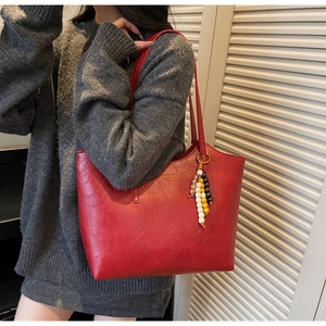 Dettaglio borsa tote rossa grande in pelle cerata con ciondolo boho di perline colorate