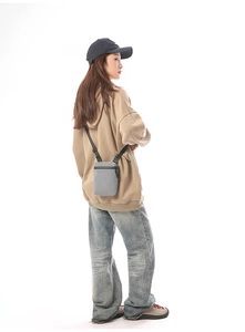 Gray nylon crossbody bag for women showing crossbody strap and compact size on model