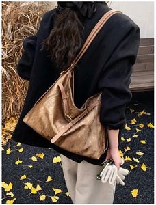 Detail of vintage brown tote bag with metallic texture and side gold buckle hardware