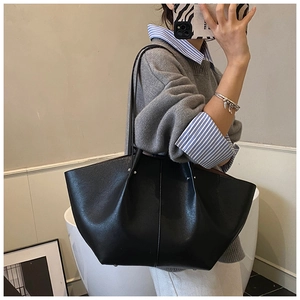Detail of a large black matte leather tote bag with wing shape and vertical stitching