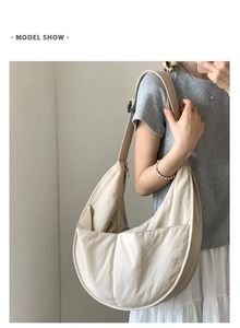 Detail of beige nylon crescent bag featuring two front pockets and wide adjustable strap