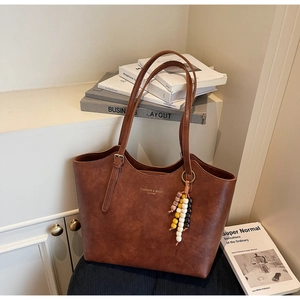 Dettaglio della borsa tote retrò marrone con logo dorato e ciondolo di perline bohémien