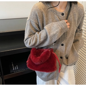 Détail du sac bandoulière en peluche rouge avec lanière en cuir noir et pompon