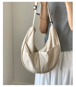 Detail of a large beige nylon dumpling bag with adjustable strap and side pockets for women