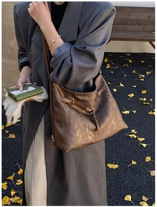 Detail of vintage brown tote bag texture and bronze buckle in an autumn park setting