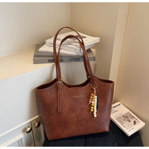 Dettaglio della borsa tote vintage in pelle marrone con ciondolo di perline colorate
