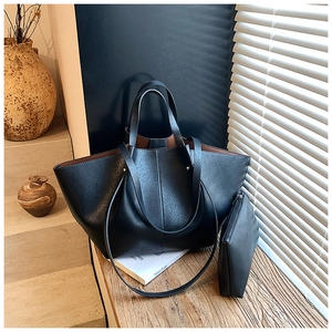 Detail view of large black faux leather tote bag with a matching zipper pouch and brown lining