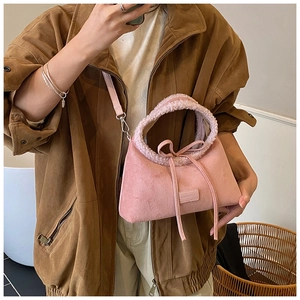 Pink matte suede tote bag with plush handle and bow detail shown on a model