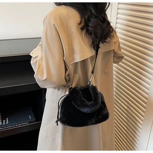 Modèle portant un sac bandoulière en fausse fourrure noire avec cordon de serrage et peluche