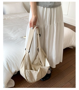 Detail view of off-white nylon dumpling bag with adjustable strap and front pocket