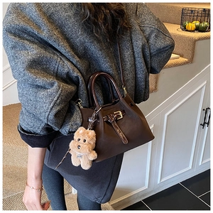 Détail du sac à main vintage en cuir marron avec breloque ours et anse marron