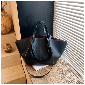 Detail of minimalist black leather tote bag with brown lining and versatile crossbody strap