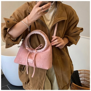 Detail of pink faux suede handbag with plush ring handle and decorative bow detail