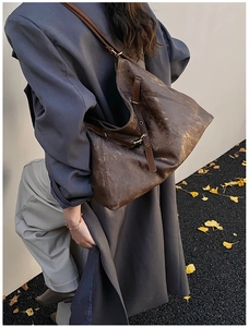 Deep brown oversized tote bag with strap details styled with long coat in autumn street