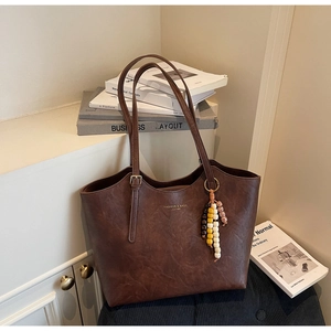Macro di una borsa tote in pelle marrone scuro con testo dorato e nappa di perline