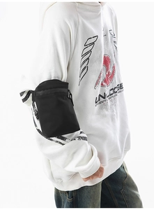 Detail of a black waterproof crossbody arm bag for sports shown on a person's sleeve