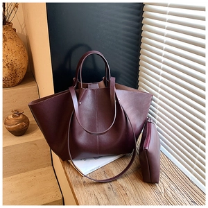 Detail of burgundy tote bag and matching pouch on a wooden surface with shadow effects