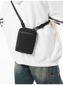 Detail view of the black crossbody bag showing its waterproof zipper and adjustable strap