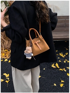 Sac seau vintage marron caramel avec porte-clés ours en peluche dans un décor d'automne