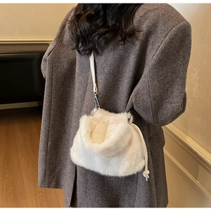 Détail d'un sac à cordon en fausse fourrure crème avec bandoulière sur un manteau
