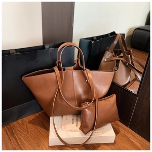 Detail of caramel brown leather tote bag set with matching pouch on a wooden display