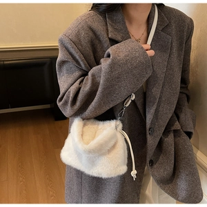 Gros plan sur un sac seau en peluche blanche avec bandoulière et cordon de serrage